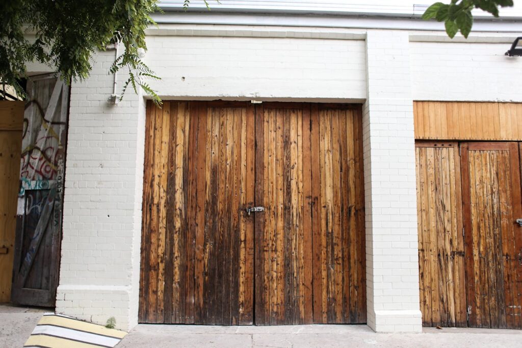 Rustic wooden garage doors set against a white brick wall, showcasing texture and urban style.